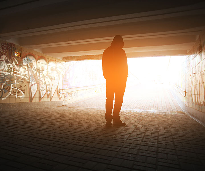 Persona sola debajo en un puente con las manos en el bolsillo Trabajando en la prevención y el bienestar universitario