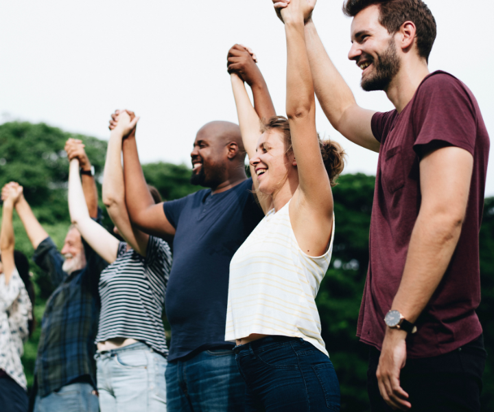 Sentidos y significados para los ciudadanos de hoy Personas en campo abierto cogidos de la mano, levantan sus brazos.