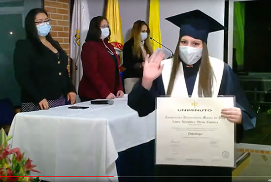 Ceremonia de grados UVD Graduada UNIMINUTO recibe su diploma con toga, birrete y tapabocas.