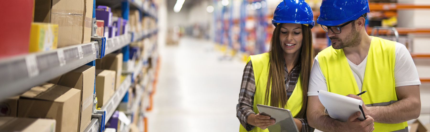 Hombre y mujer revisan tabla de inventarios en bodega de almacenamiento