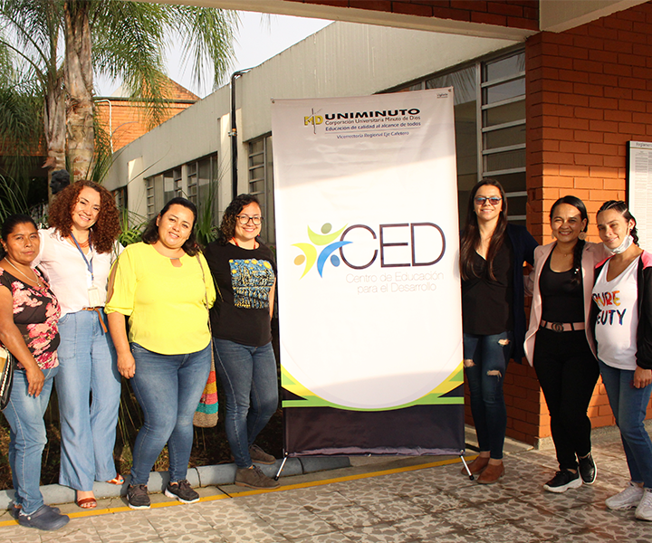 Personas beneficiarias del taller posando frente a pendón blanco con logo del CED, en UNIMINUTO Pereira. Proyecto “Territorios y Marcas” dialogando con las comunidades en Pereira.