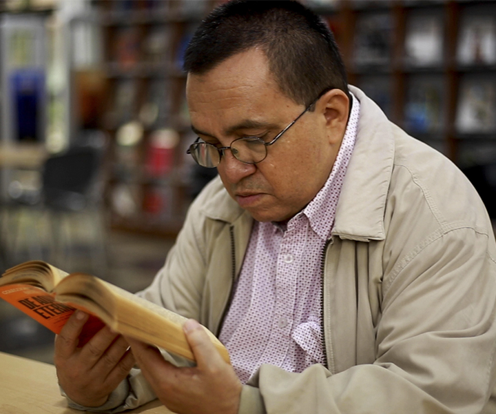 Docente José Eucario Parra Castrillón de UNIMINUTO leyendo un libro en la biblioteca Experiencias de aprendizaje virtual, fueron socializadas en FILBO 2022