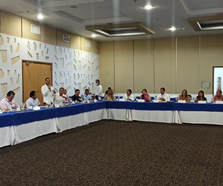 UNIMINUTO y el empresariado Regional del Caribe unidos por los beneficios tributarios 2022 un hombre de pie hablando hacía varias personas sentadas en sillas en forma de U
