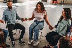 Personas en circulo sentadas tomadas de la mano