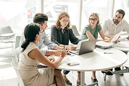 Equipo de trabajo dialogando en mesa con computador