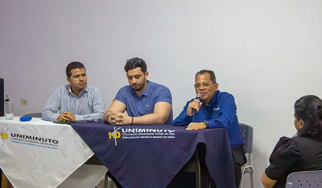 Mesa principal del IX Coloquio de Posgrados con José Albeiro Tamara, Brian Bustos y José Alberto Cristancho, quien se dirige al público con un micrófono