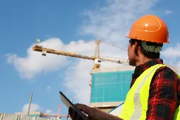 obrero con casco en construcción con grúa de fondo