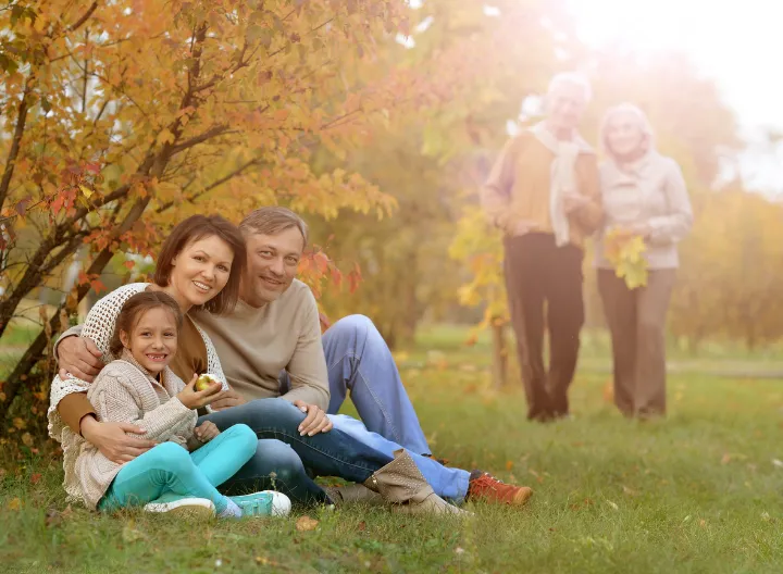  Familia comparte en el parque, sentados en el pasto sonrien. 