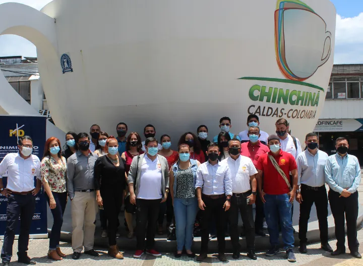 Integrantes de las delegaciones de uniminuto y CINOC junto a la taza de café más grande del mundo, ubicada en el parque de chinchiná.
