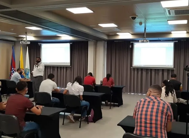 Grupo de personas en un salón recibiendo una charla