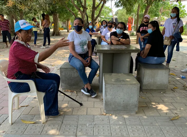 Mujer hablándole a varios jóvenes en una plaza 
