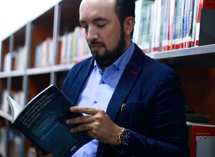 Profesor Miguel Barreto de UNIMINUTO sosteniendo el libro “Una estrategia curricular para el fomento de la cultura de las paces en el ámbito universitario”