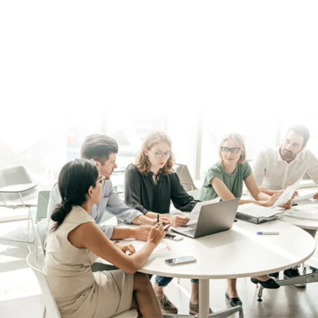 Equipo de trabajo dialogando en mesa con computador