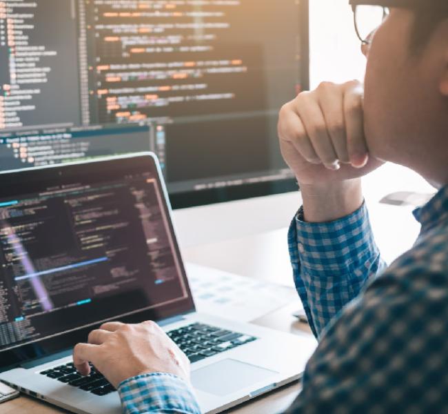 Persona tocando la pantalla de un un computador señalando lenguaje de programacion