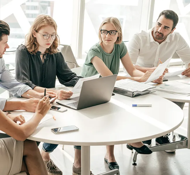 Equipo de trabajo dialogando en mesa con computador
